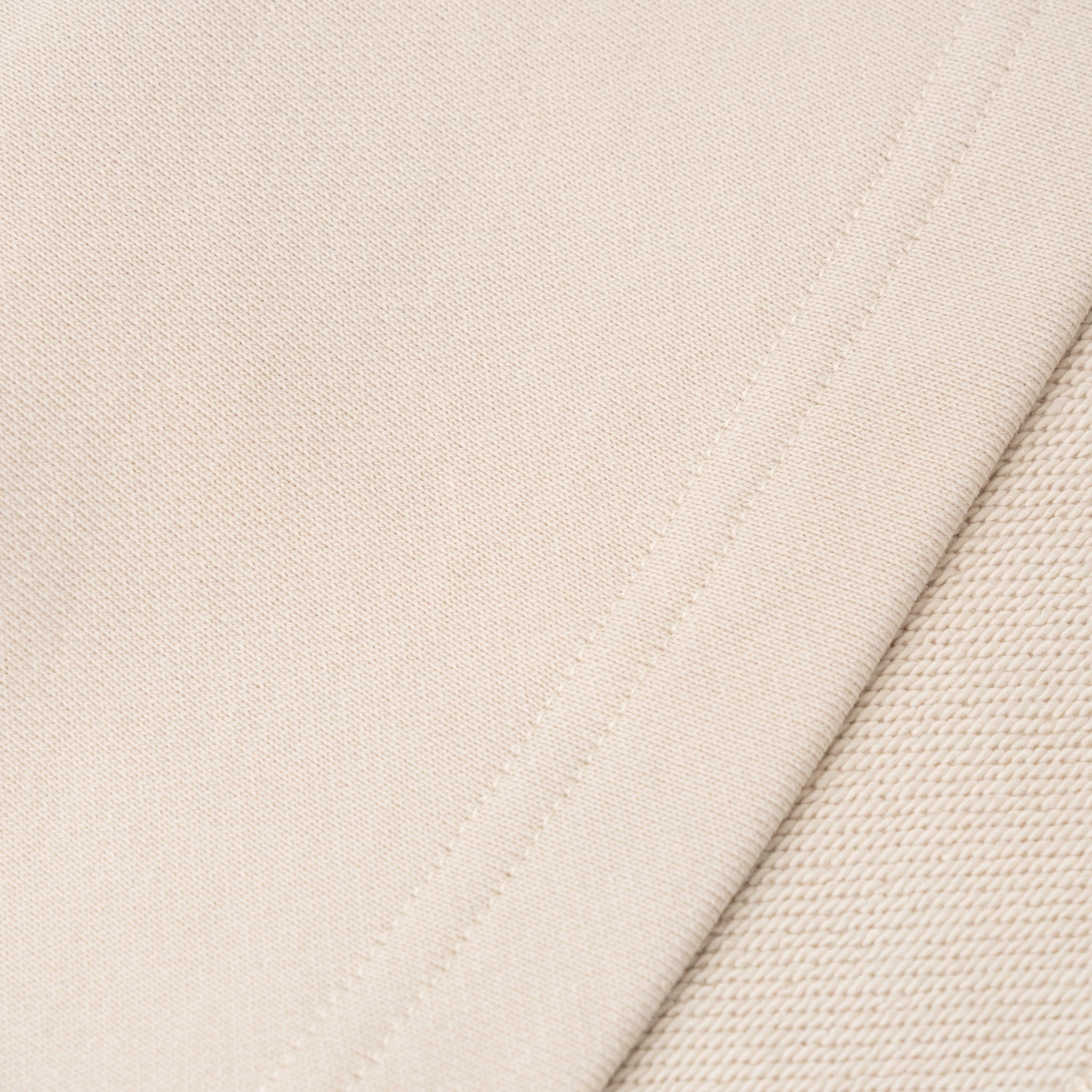 Close-up of beige Ninepine organic cotton terry fabric texture with stitching detail.